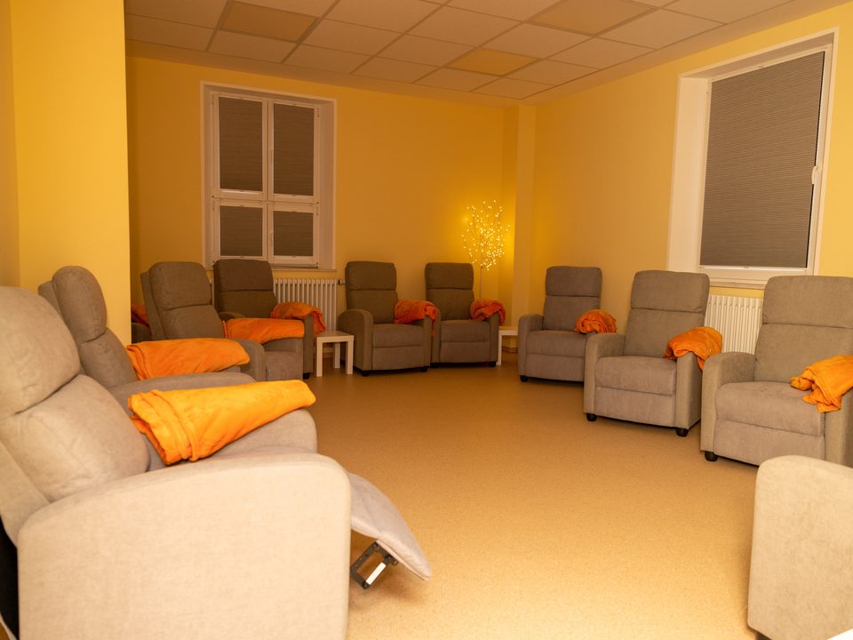 Ruheraum mit Liegesesseln und orangefarbenen Decken in warmem Licht